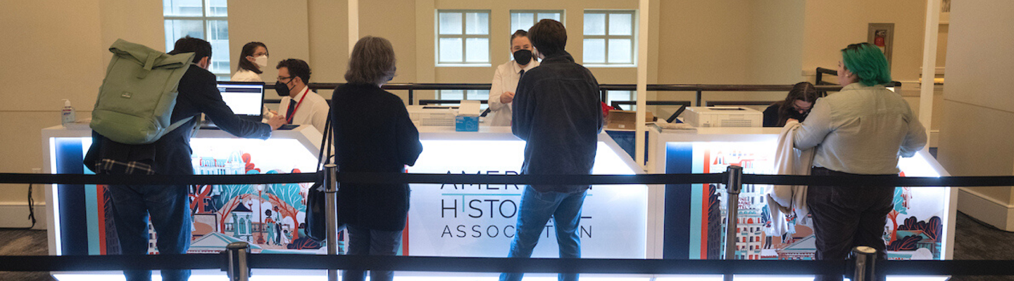 Conference attendees checking in at AHA23 with signs that read "American Historical Association"